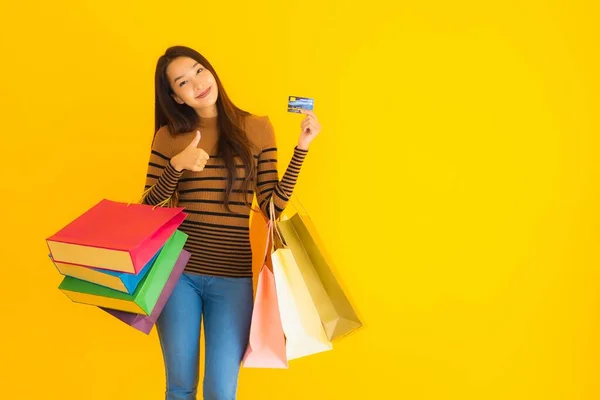 아름다운 아시아 여자가 노란색외진 배경에 이있는 쇼핑용 카드를 사용하는 — 스톡 사진