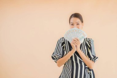 Kahverengi arka planda parası ve parası olan güzel bir Asyalı kadın portresi.