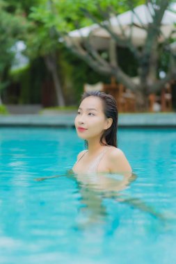 Güzel bir Asyalı kadın portresi. Rahat bir tatil için otel havuzunda yüzme havuzu etrafında gülümse.
