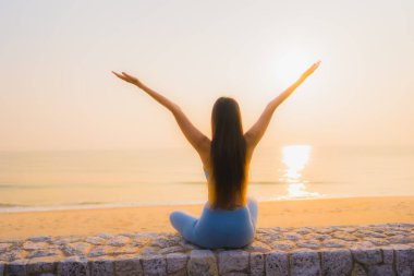 Genç Asyalı kadının portresi sağlık için gün doğumunda deniz kıyısı okyanusunda meditasyon yapıyor.