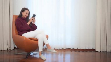 Evde akıllı telefon kullanan Asyalı güzel bir kadının görüntüleri.