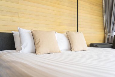 Otel odasındaki yatak odasının iç dekorasyonunda beyaz rahat yastık.