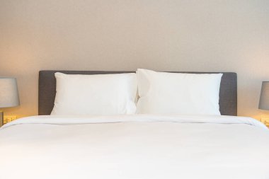 Yatak odasının iç dekorasyonuna beyaz yastık ve battaniye. İçinde lamba var.