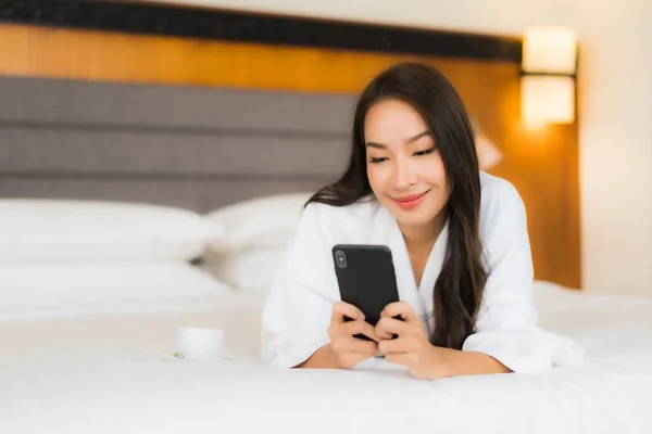 在卧室的内部 漂亮的亚洲年轻女子在床上使用智能手机 — 图库照片