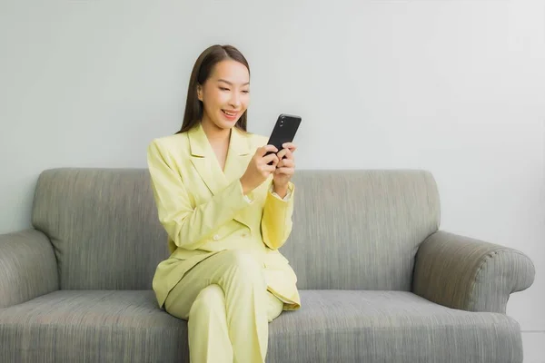 肖像画美しい若いアジアの女性使用スマートフォン上のソファの上にリビングルームのインテリア — ストック写真