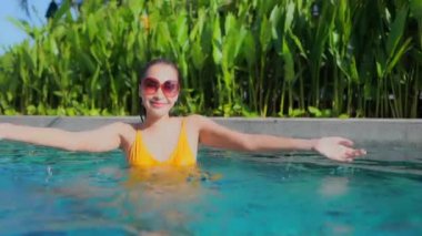 Güzel Asyalı bir kadının oteldeki havuzda dinlenirken çekilmiş görüntüleri.