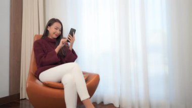 Evde akıllı telefon kullanan Asyalı güzel bir kadının görüntüleri.