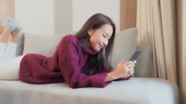 Evde akıllı telefon kullanan Asyalı güzel bir kadının görüntüleri.