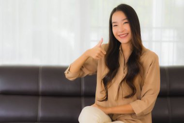 Güzel bir Asyalı kadın portresi. Mutlu bir gülümseme. Oturma odasındaki kanepede rahatla.