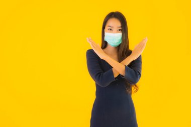 Koronavirüsten korunmak için maske takmış güzel Asyalı bir kadın portresi ve sarı izole edilmiş arka planda 19 numara.