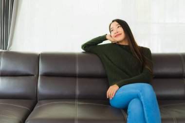 Güzel bir portre. Genç Asyalı kadın. Oturma odasındaki kanepede rahatla.