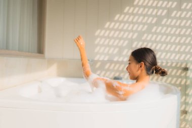 Portre genç Asyalı kadın rahatla spa konsepti için küvette banyo yap.