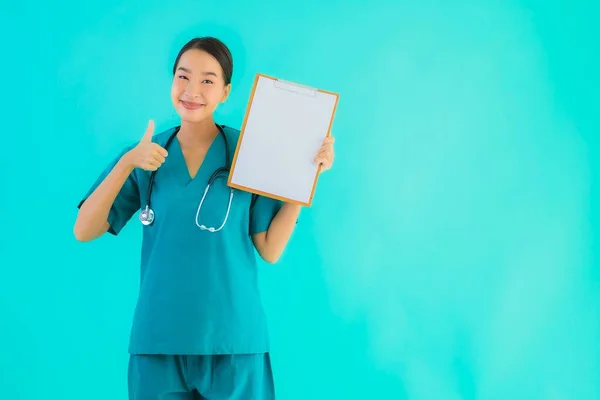 Portrait beautiful young asian doctor woman with empty paper board for copy space on blue isolated background - Healthcare in hospital and clinic concept