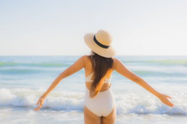 Güzel bir Asyalı kadın portresi. Okyanus sahillerinde mutlu bir gülümseme ve tatil için mavi bir gökyüzü.