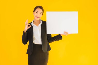 Güzel bir portre. Genç Asyalı kadın, sarı izole edilmiş arka planda boş beyaz tahta gösteriyor.