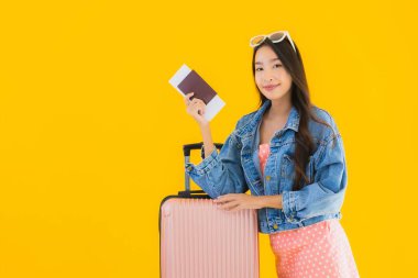 Çantalı güzel Asyalı kadın. Pasaportu ve sarı izole bir arka planda bilet.