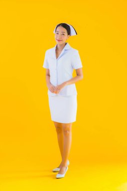 Güzel Asyalı genç Taylandlı hemşirenin portresi klinikteki ve hastanedeki hastalar için sarı izole edilmiş arka planda birçok eylem çalışmasında yer alıyor.