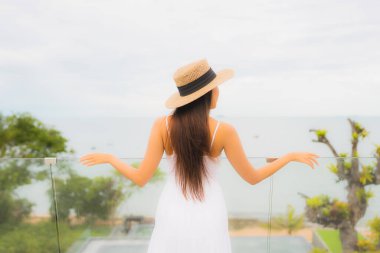 Portriat güzel genç Asyalı kadın deniz manzaralı balkonda mutlu bir gülümseme