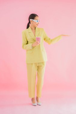 3D gözlüklü ve patlamış mısırlı güzel Asyalı kadın renkli arka planda film izlemeye hazır.