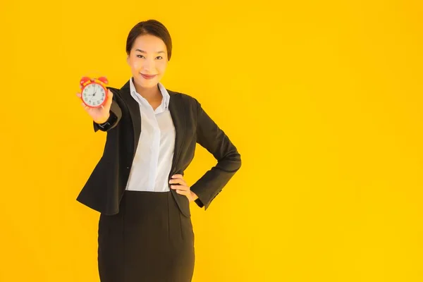 在黄色孤立的背景上 亚洲年轻貌美的女人表现出时钟或警报的时间 — 图库照片