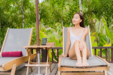 Portre güzel Asyalı kadın gülümsemesi tatil gezisinde tatil otelinde yüzme havuzunda rahatla.