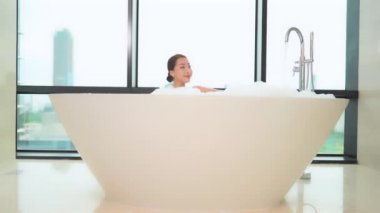 Güzel Asyalı kadının sabun köpüğüyle banyo yaptığı görüntüler.