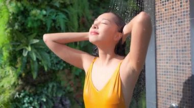 Güzel Asyalı bir kadının açık havada duş alırken çekilmiş görüntüleri.