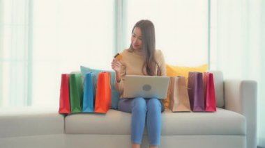 Asyalı güzel bir kadının dizüstü bilgisayar ve kredi kartıyla e-alışveriş yaptığı görüntüler.