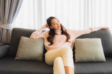 Güzel bir Asyalı kadın portresi. Oturma odasında rahatlamak için koltuğa oturur.