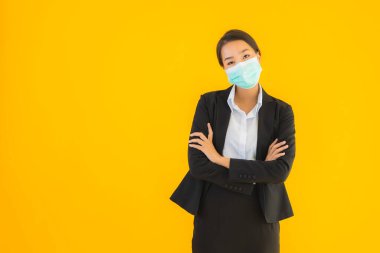 Güzel genç iş kadını portresi Korunmak için maske takıyor 19 koronavirüs sarı izole arka planda