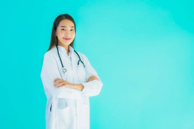 Klinikte ya da mavi izole edilmiş arka planda hastanede kullanmak üzere steteskoplu güzel Asyalı genç doktor kadın portresi.