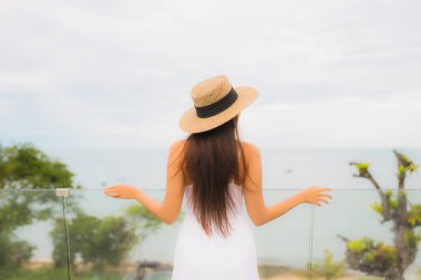 Portriat güzel genç Asyalı kadın deniz manzaralı balkonda mutlu bir gülümseme