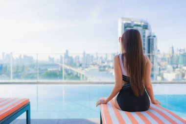 Güzel bir Asyalı kadının portresi tatil gezilerinde yüzme havuzunda rahatlar.