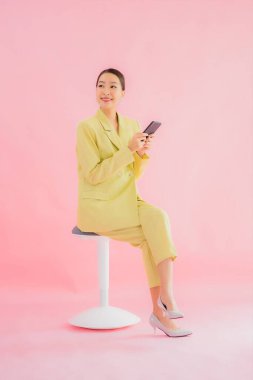 Güzel Asyalı iş kadını portresi. Arka planda kahve fincanı ve akıllı cep telefonu kullanıyor.