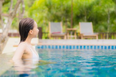 Portre güzel Asyalı kadın gülümsemesi tatil gezisinde tatil otelinde yüzme havuzunda rahatla.