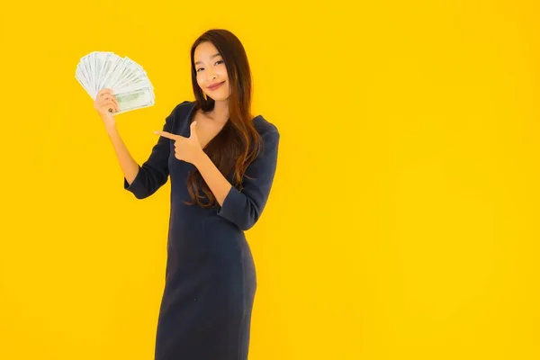 肖像画美しいです若いですアジアの女性とともにお金と現金上の黄色隔離された背景 — ストック写真