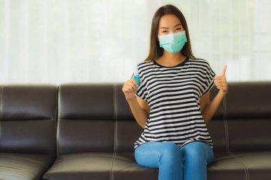 Güzel Asyalı genç bir kadının portresi Coronavirus 'tan elini temizlemek için alkol spreyi kullanıyor ya da evde covid19 kullanıyor.