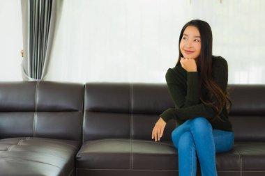 Güzel bir portre. Genç Asyalı kadın. Oturma odasındaki kanepede rahatla.