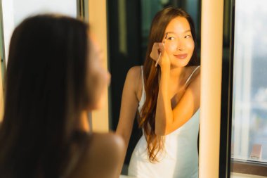 Güzel bir Asyalı kadın portresi makyaj malzemesi makyaj malzemesi ve yüz makyajı ile banyo içinde yüz maskesi.