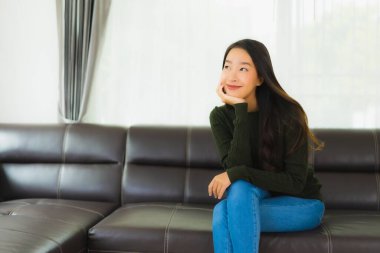 Güzel bir portre. Genç Asyalı kadın. Oturma odasındaki kanepede rahatla.