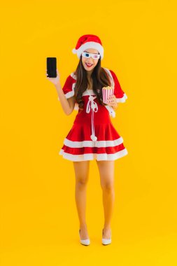 Güzel bir Asyalı kadın portresi patlamış mısır ve 3D gözlüklü noel şapkası takıyor sarı izole edilmiş arka planda film izlemeye hazır.