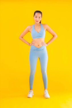 Sarı izole edilmiş arka planda spor giysili güzel Asyalı kadın portresi egzersize hazır.