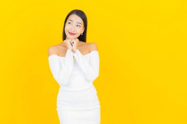 Portre güzel genç iş kadını gülümseyen ve eylem sarı arka planlı Asyalı kadın