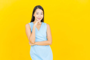 Asyalı güzel bir kadının portresi. Sarı arka planda hareketli gülümsüyor.