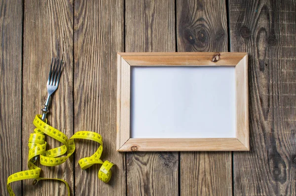 Diet concept, fork and measuring tape on wooden background. Fork and measuring tape on wooden background for a healthy lifestyle — Stock Photo, Image