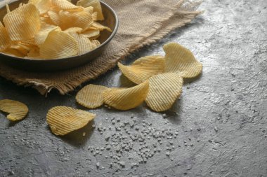 Eski mutfak masasında bir hasır kase gevrek patates cipsi