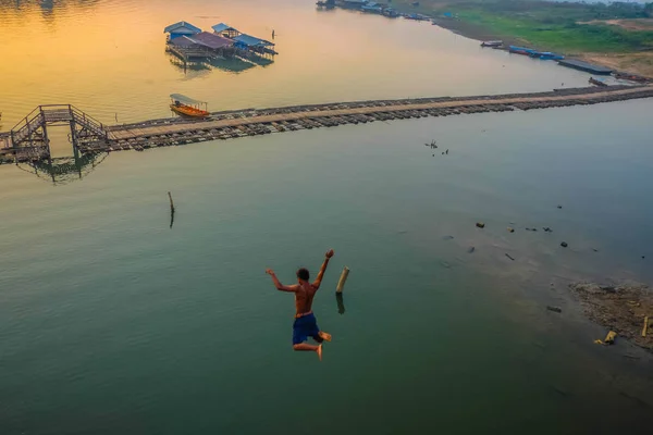 Asian Guy Jump from Mon Bridge in sangkhlaburi kanchanaburi bangkok thailand,Famous Jumping point from Mon Bridge sangkhlaburi,dangerous Jumping in songgaria rive