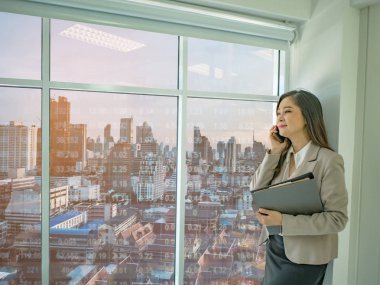 Modern iş kadınları hakkında borsa cityscape stok numarası, iş concep ile pencereden dışarı bakarak beyaz mobilephone konuşmak kullanın