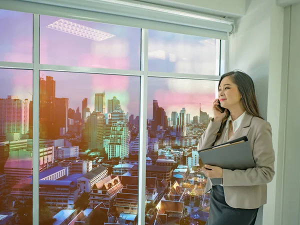 Modern iş kadınları hakkında borsa cityscape stok numarası, iş concep ile pencereden dışarı bakarak beyaz mobilephone konuşmak kullanın