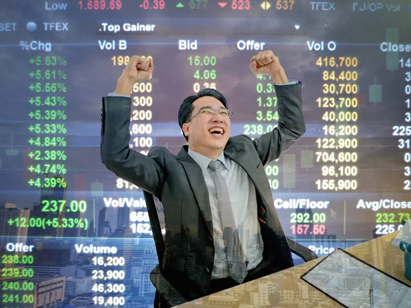 Onun borsa çünkü büyümesini, borsa arka plan, iş concep ile onun masasında oturan iş adamı çok mutlu oturan Asya iş adamı